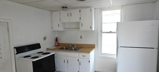 kitchen featuring sink, white appliances, white cabinets, and a wealth of natural light