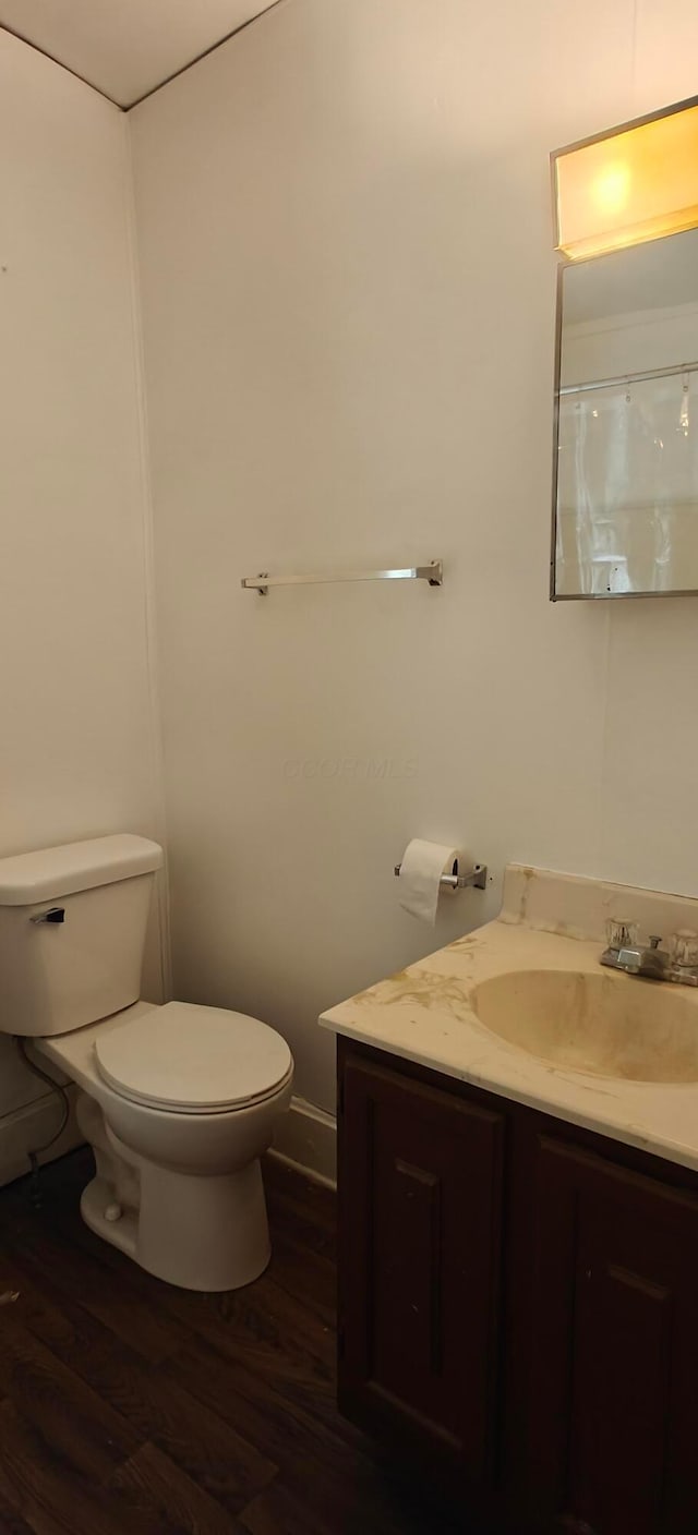 bathroom with wood-type flooring, toilet, and vanity