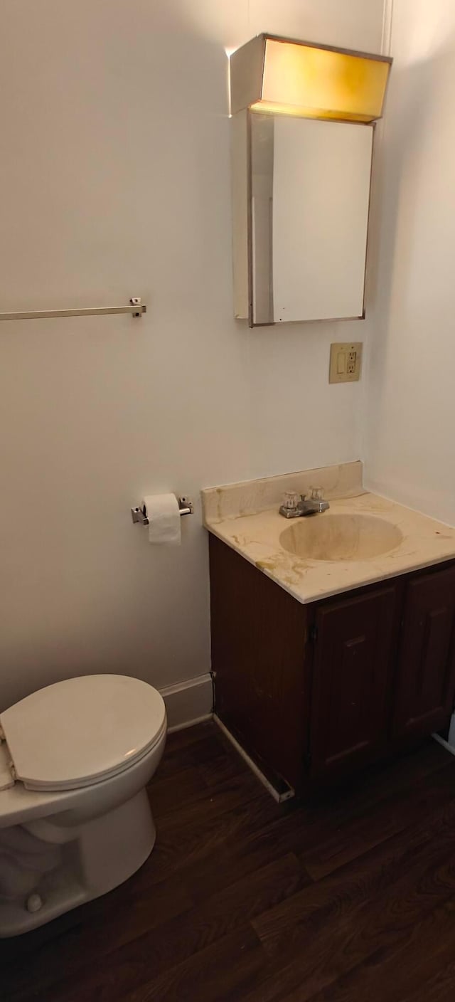 bathroom with hardwood / wood-style flooring, toilet, and vanity