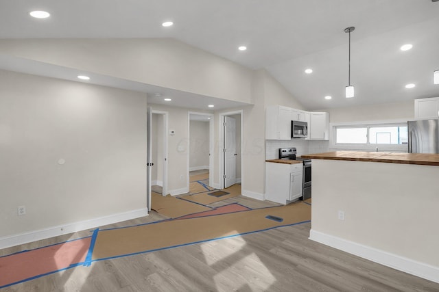 kitchen featuring wooden counters, appliances with stainless steel finishes, hanging light fixtures, high vaulted ceiling, and white cabinetry