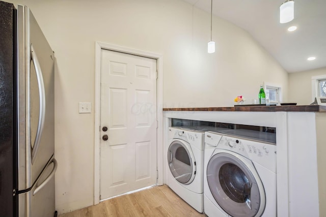 clothes washing area featuring light hardwood / wood-style flooring and washer and clothes dryer