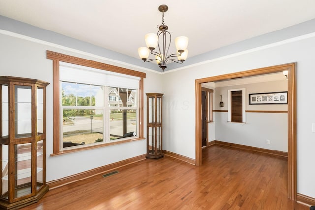 spare room featuring hardwood / wood-style floors and an inviting chandelier