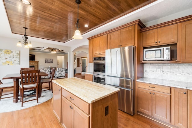 kitchen with pendant lighting, stainless steel appliances, a tray ceiling, and a kitchen island