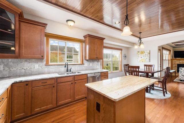 kitchen with sink, a center island, a fireplace, decorative light fixtures, and stainless steel dishwasher