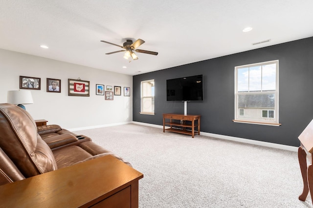 living room with a wealth of natural light, ceiling fan, and carpet flooring