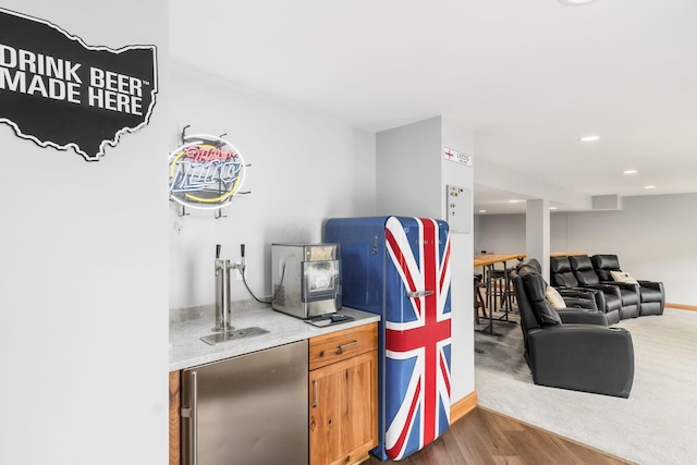 bar with dark wood-type flooring and stainless steel fridge