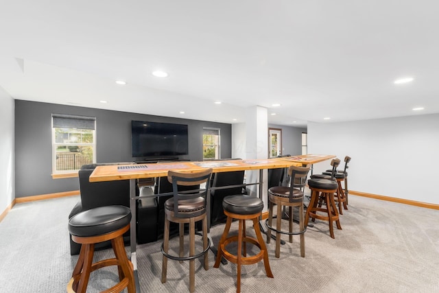 bar with light colored carpet, wooden counters, and plenty of natural light