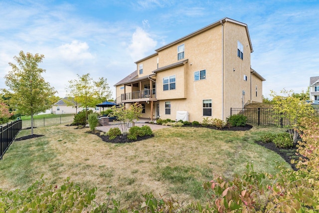 back of property featuring a balcony, a yard, and a patio