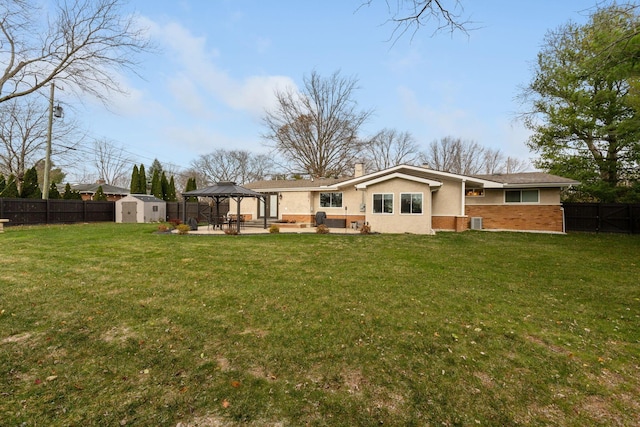 back of property featuring a gazebo, a shed, a yard, and a patio