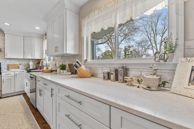 kitchen featuring dishwasher, dark wood-type flooring, white cabinets, sink, and tasteful backsplash