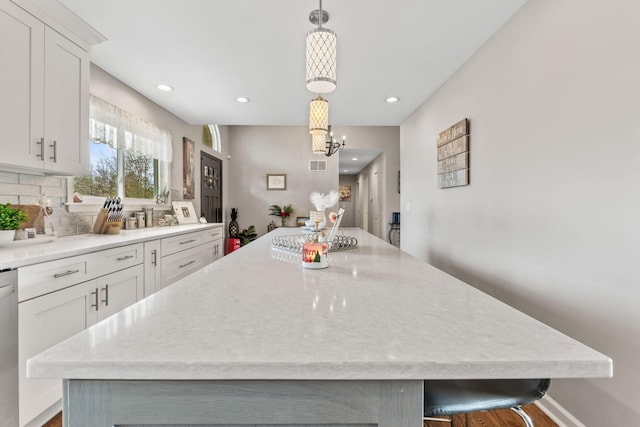 kitchen featuring a kitchen breakfast bar, a spacious island, white cabinetry, and hanging light fixtures