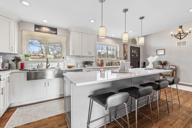 kitchen with a breakfast bar, white cabinetry, a center island, and dark hardwood / wood-style floors