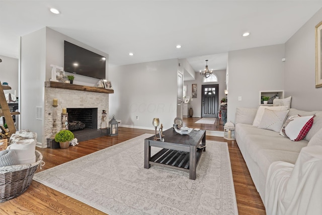 living room with hardwood / wood-style flooring, a notable chandelier, and a tiled fireplace