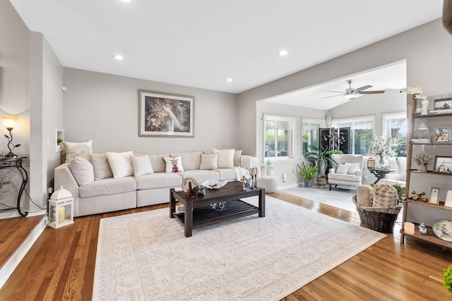 living room with ceiling fan, wood-type flooring, and vaulted ceiling