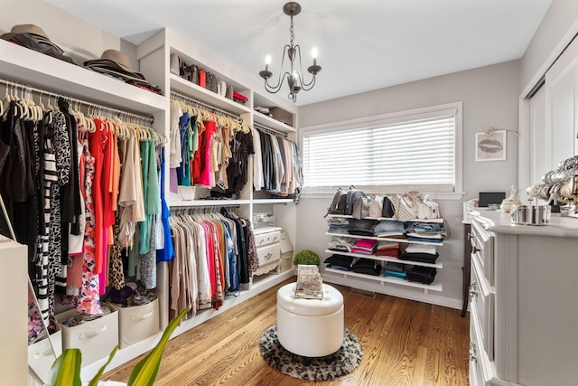 walk in closet featuring hardwood / wood-style floors and a notable chandelier