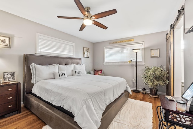 bedroom featuring a barn door, ceiling fan, and light hardwood / wood-style flooring