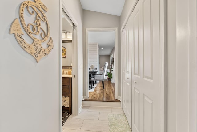 hallway featuring light tile patterned flooring and vaulted ceiling