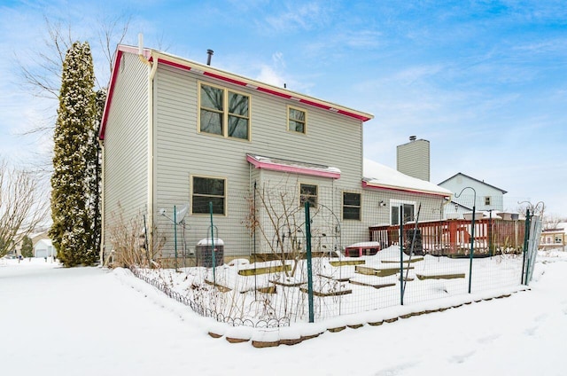 snow covered back of property featuring a wooden deck