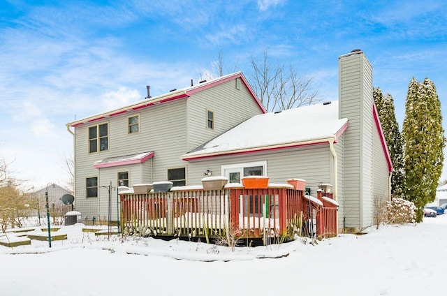 snow covered back of property featuring a wooden deck