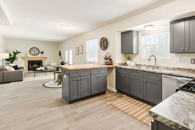 kitchen featuring sink, light hardwood / wood-style flooring, kitchen peninsula, a healthy amount of sunlight, and gray cabinetry