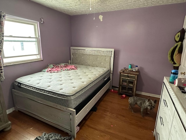 bedroom featuring a textured ceiling and dark hardwood / wood-style flooring