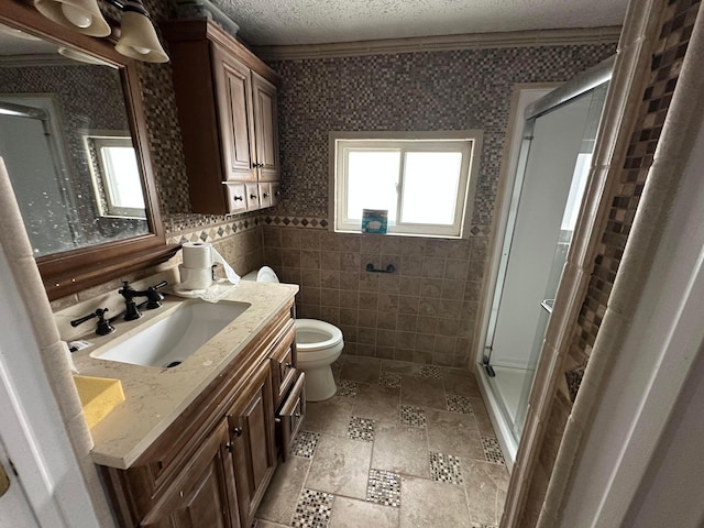 bathroom with a shower with shower door, tile walls, a textured ceiling, ornamental molding, and vanity