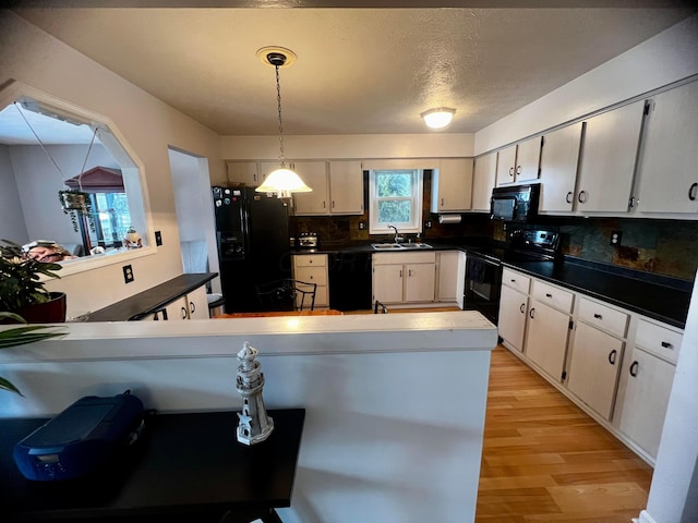 kitchen with black appliances, kitchen peninsula, sink, decorative light fixtures, and tasteful backsplash