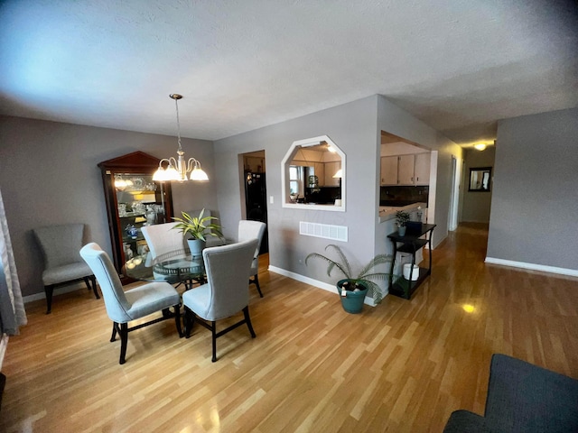 dining space featuring a textured ceiling, an inviting chandelier, and wood-type flooring