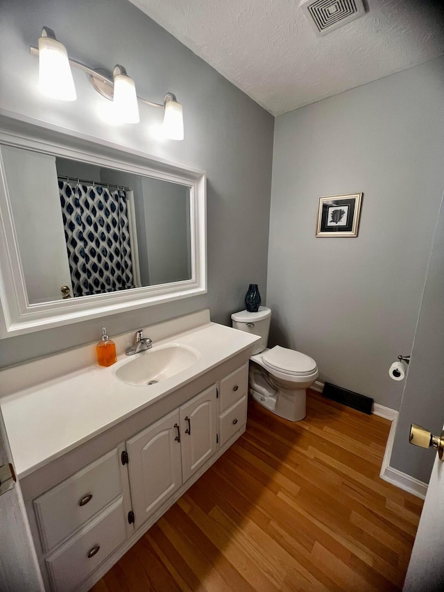 bathroom featuring hardwood / wood-style floors, a textured ceiling, toilet, and vanity