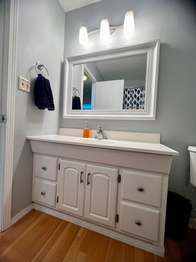 bathroom with toilet, vanity, and hardwood / wood-style flooring