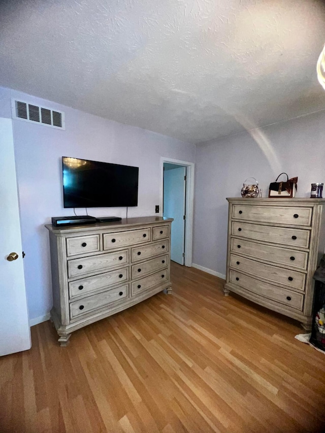 bedroom with a textured ceiling and light hardwood / wood-style flooring