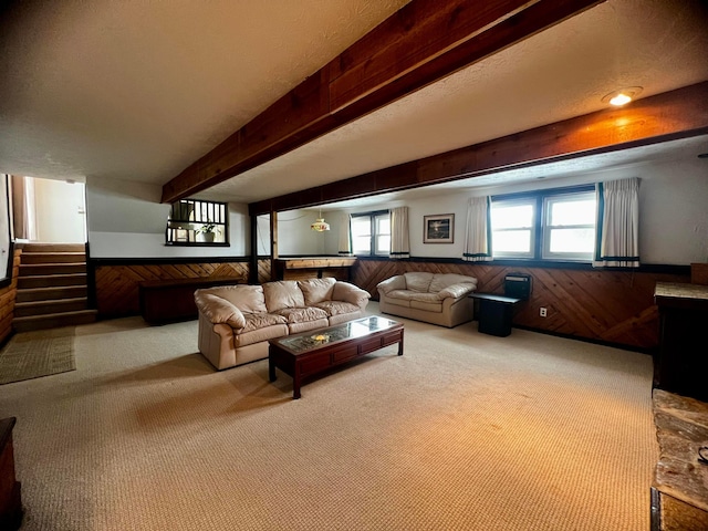 carpeted living room with wooden walls and beamed ceiling