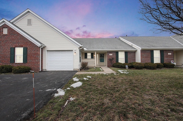 ranch-style home featuring a garage, a yard, and covered porch