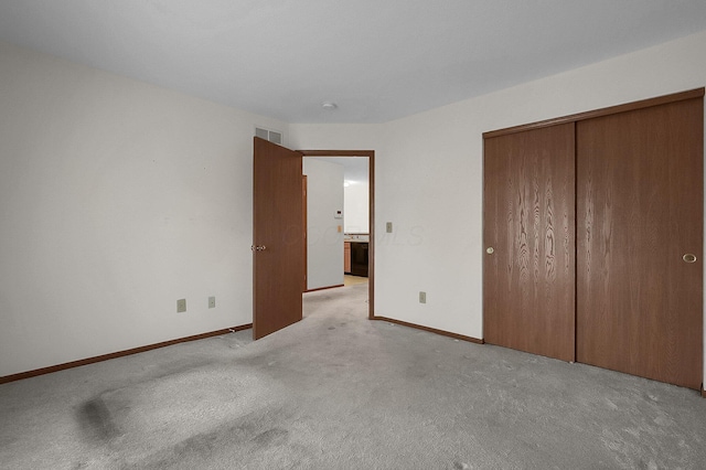 unfurnished bedroom featuring light colored carpet and a closet