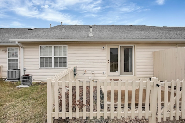 rear view of house featuring central AC and a lawn