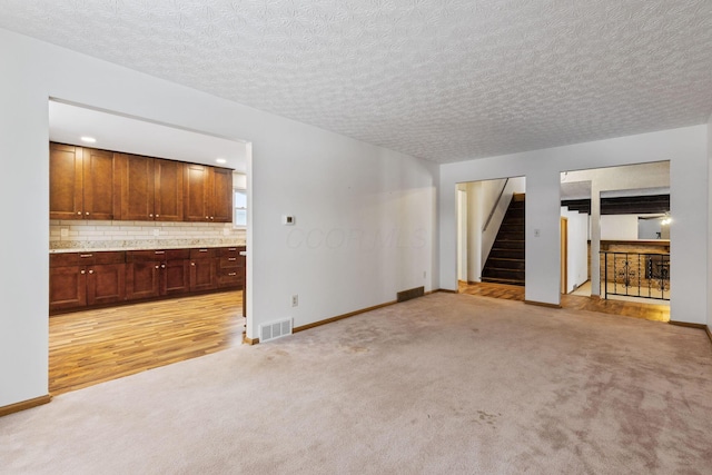 unfurnished living room featuring a textured ceiling and light carpet