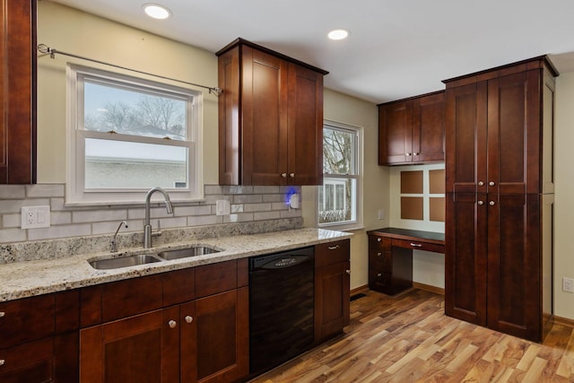 kitchen with light stone countertops, a healthy amount of sunlight, sink, black dishwasher, and light hardwood / wood-style flooring