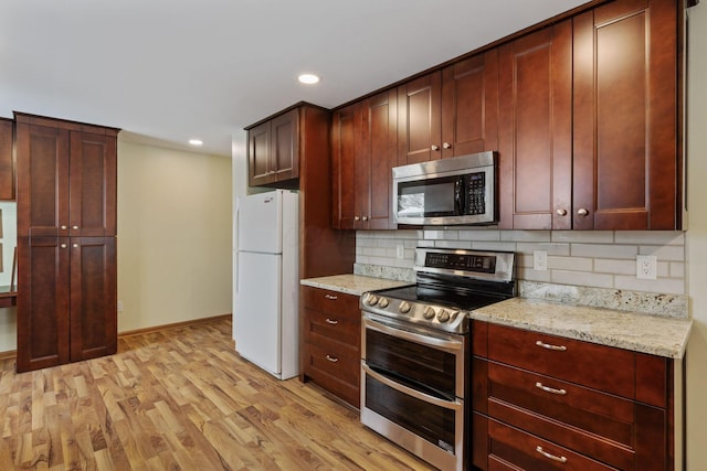 kitchen featuring decorative backsplash, light hardwood / wood-style floors, light stone counters, and appliances with stainless steel finishes