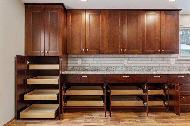 details with light stone counters, light wood-type flooring, and tasteful backsplash