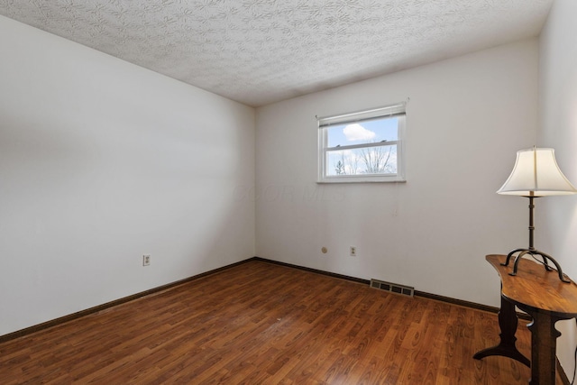 empty room with a textured ceiling and dark hardwood / wood-style floors