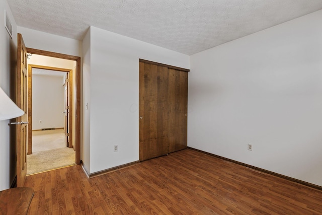 unfurnished bedroom with hardwood / wood-style flooring, a textured ceiling, and a closet