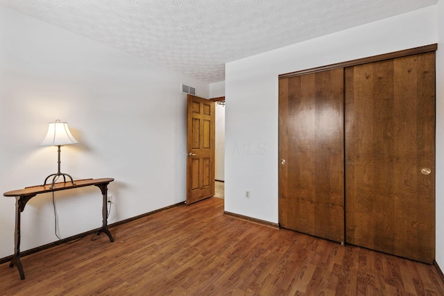 unfurnished bedroom with a closet, hardwood / wood-style floors, and a textured ceiling