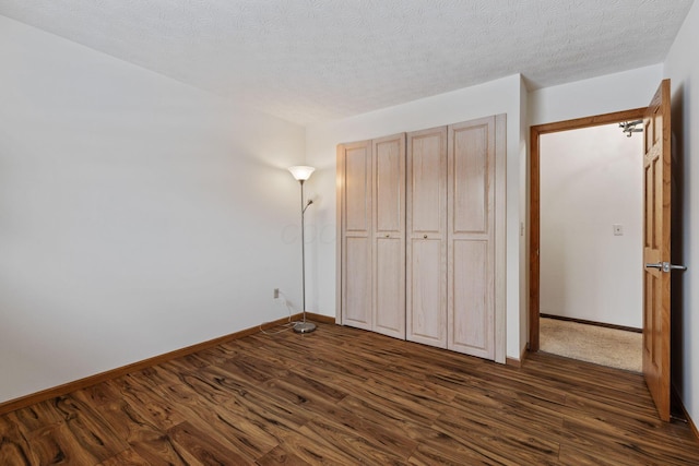 unfurnished bedroom featuring a textured ceiling, dark wood-type flooring, and a closet