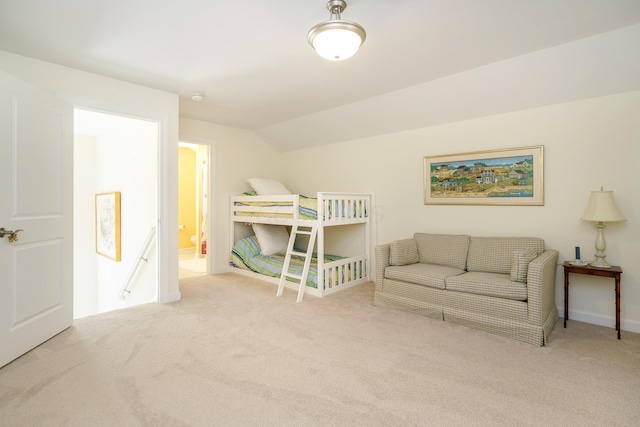 bedroom featuring light carpet, connected bathroom, and vaulted ceiling