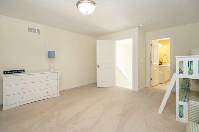 bedroom with connected bathroom and light carpet