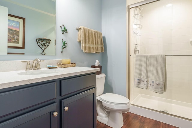 bathroom featuring wood-type flooring, toilet, walk in shower, and vanity