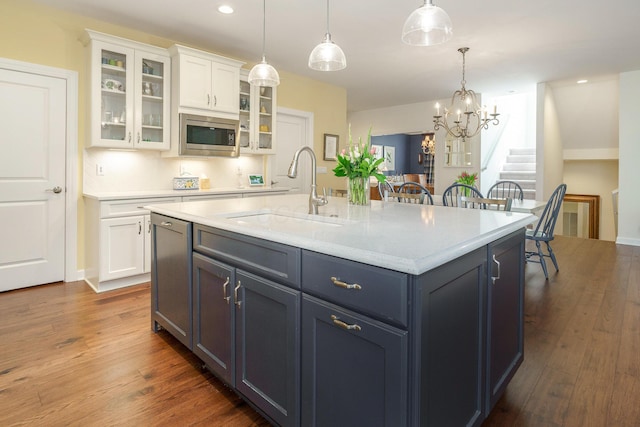 kitchen featuring appliances with stainless steel finishes, white cabinets, decorative light fixtures, sink, and dark wood-type flooring