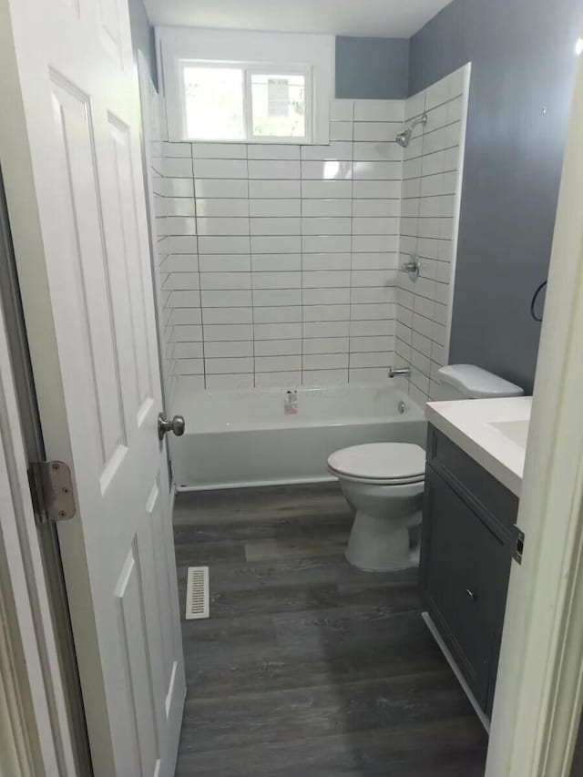 full bathroom with vanity, hardwood / wood-style flooring, toilet, and tiled shower / bath combo