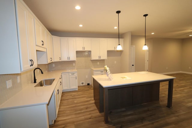 kitchen featuring pendant lighting, a kitchen island, sink, white cabinetry, and dark hardwood / wood-style floors