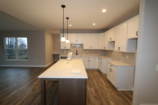 kitchen featuring a center island, white cabinetry, sink, and decorative light fixtures